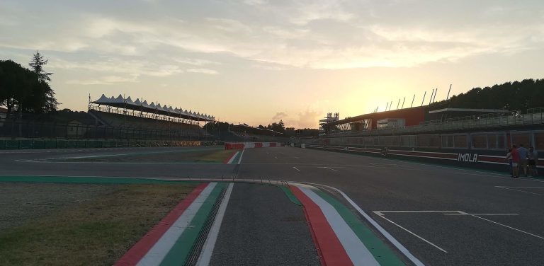 Autodromo Enzo and Dino Ferrari in Imola Rennstrecke mit mehreren Fahrzeugen und einer Kurve in einer grünen Umgebung.