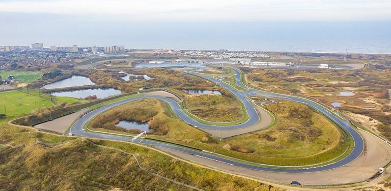 Circuit Zandvoort Kurvenreiche Straße zwischen Hügeln, umgeben von Wasserflächen und Grünland.